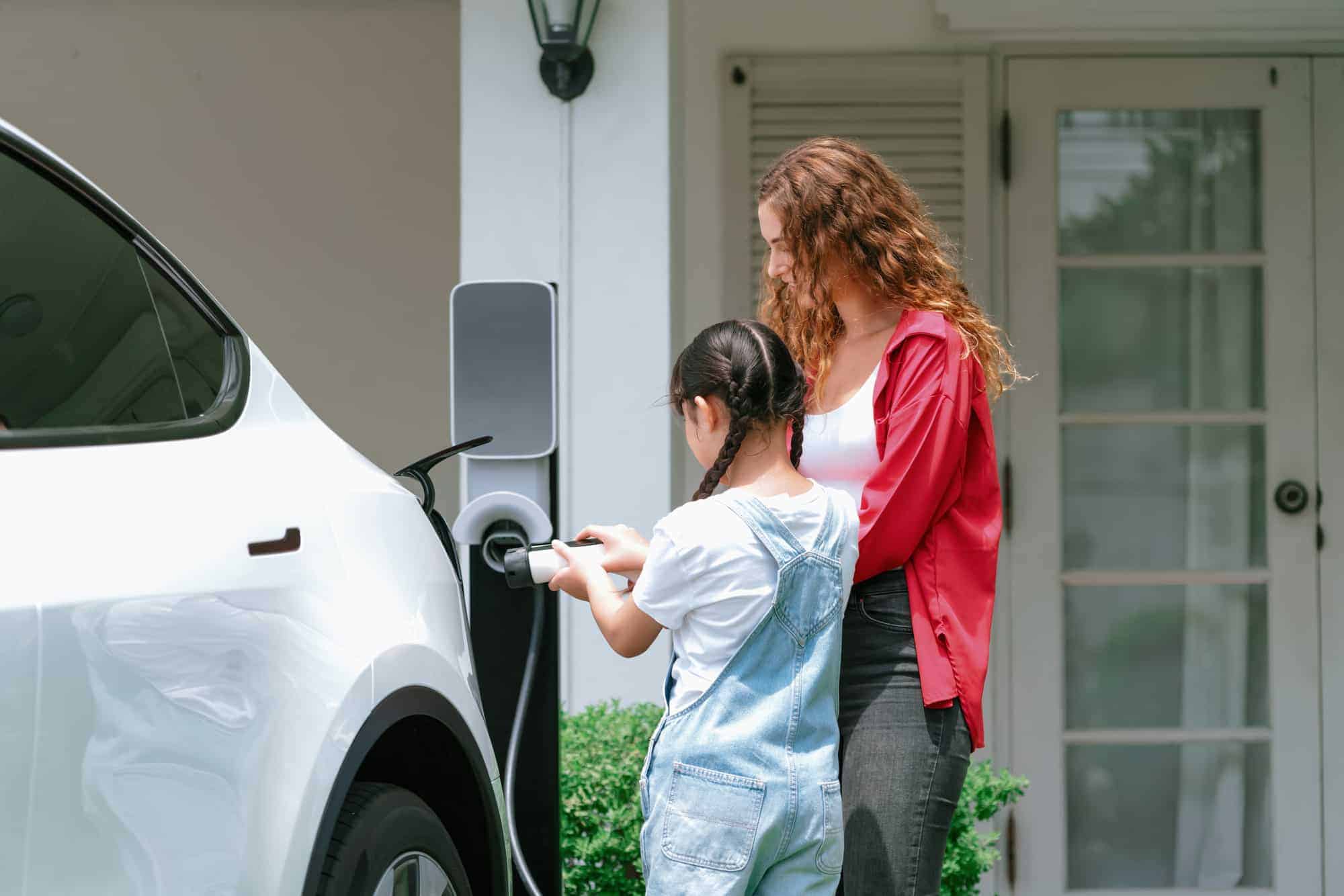 Photo of a woman and her daughter plugging in an EV car